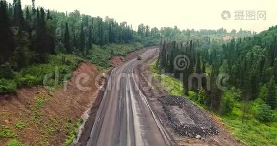 森林道路全景。 林中乡村道路上的倾卸车的鸟瞰图。 从泰加无人机的视野视频