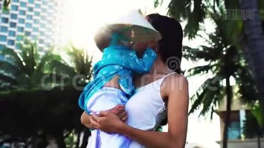 一位母亲把她的小女儿抱在手心附近的海滩上。视频