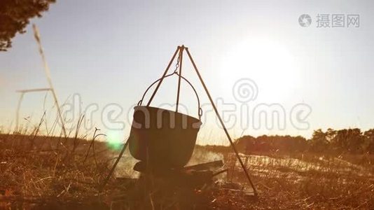 点燃篝火徒步旅行者停在营地，徒步旅行者的水在水壶里沸腾，保龄球锅在日落时点燃阳光视频