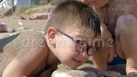 小男孩被埋在海边的沙滩上视频