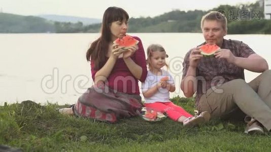 大家一起吃西瓜快乐的一家人在夏日的池塘边野餐视频