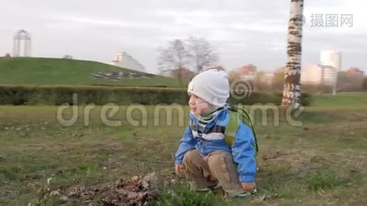 可爱的孩子在日落时和他妈妈在公园里玩。 他坐着，然后站起来。 镜头围绕着男孩转视频