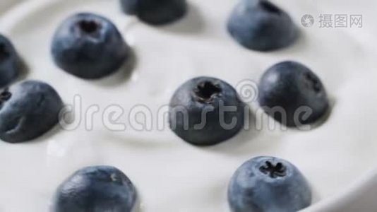 特写蓝莓在天然酸奶旋转。 4k. 水果背景。视频