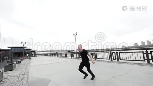 一个自由奔跑的追踪金发男人在公园里跳着翻板跑酷视频