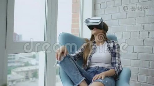 年轻女性使用虚拟现实耳机坐在阳台上的椅子上有VR体验。视频