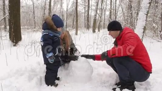 一家人带着孩子在公园堆雪人。视频