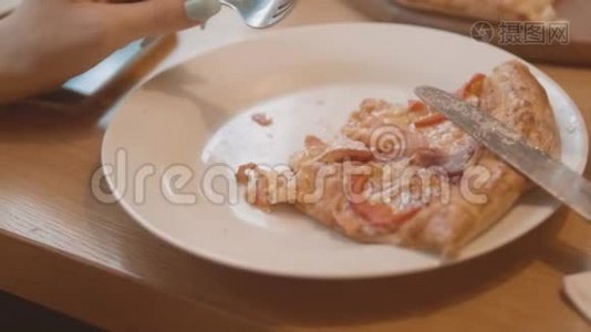 在一个咖啡馆的慢动作视频中，一片披萨躺在盘子里。 快餐披萨食品概念视频