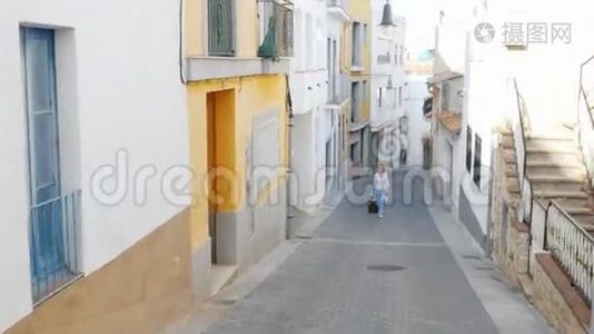 带着旅行袋的游客沿着西班牙老欧洲城市的狭窄街道走去视频