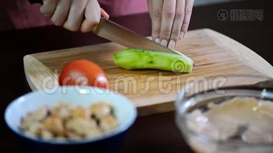 女人切黄瓜。 雌性手切绿色黄瓜环。视频
