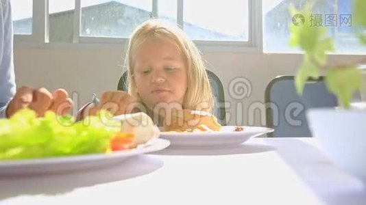 小金发女孩在桌旁用鸡盘放勺子视频