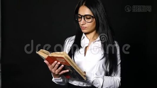 肖像吸引人的女人读书。 一位年轻漂亮的黑发女郎，留着一头长发，穿着工作室里视频