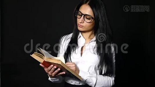 肖像吸引人的女人读书。 一位年轻漂亮的黑发女郎，留着一头长发，穿着工作室里视频