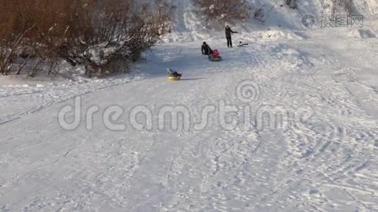 小女孩从山上滑下雪管，两个无法辨认的大人和小孩在山上视频