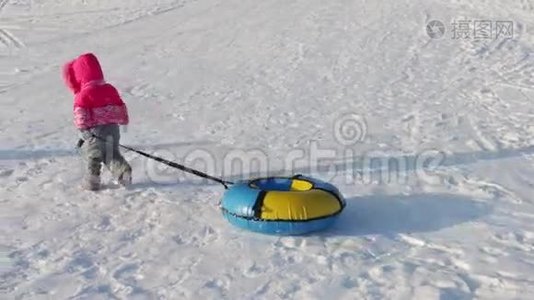 小女孩从山上滑下雪管，两个无法辨认的大人和小孩在山上视频