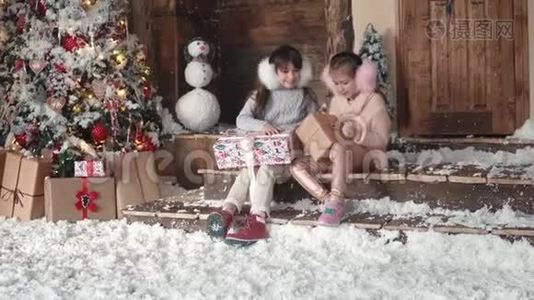 圣诞节或新年。 孩子们正在看漂亮的圣诞盒子里的礼物。 两个小女孩在圣诞节视频