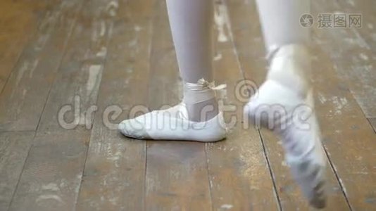 在芭蕾训练期间，一个穿白色芭蕾舞鞋的女孩`在一个旧木地板上的腿特写。 古典元素视频