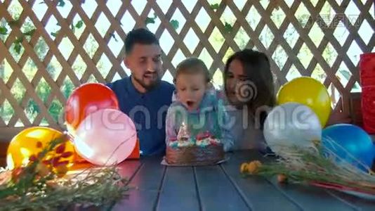 小女孩和父母坐在一起，在生日蛋糕上吹蜡烛视频