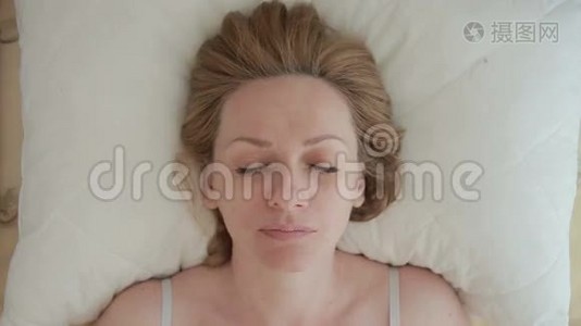 一个躺在床上的女人睁开眼睛微笑。 特写镜头。 从上面看视频