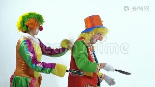 两个马戏团小丑扔出一个玩具煎饼，然后用煎锅把它抓起来视频