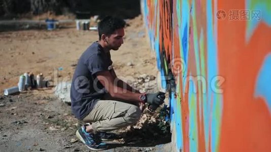 涂鸦艺术家在街墙上画画。 帅气的男人用喷雾瓶喷着五颜六色的油漆，城市视频