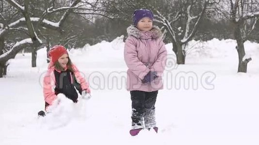 快乐的孩子们在雪地里玩耍的慢动作。 两个快乐的女孩在冬天外面玩视频