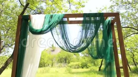 婚礼木制拱门，绿色和白色织物。视频