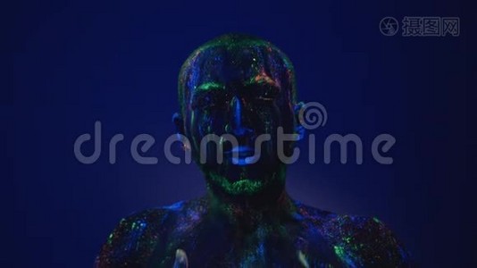 一个人在紫外线下从脸上擦荧光粉。 在生活环境前的空虚。视频