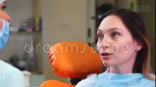 牙科柜里的快乐女病人。 病人和牙医之间的谈话视频