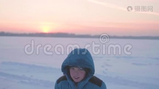一个孩子在冬天户外玩耍，跑步，把雪扔到顶部。 美丽的日落。 户外运动视频