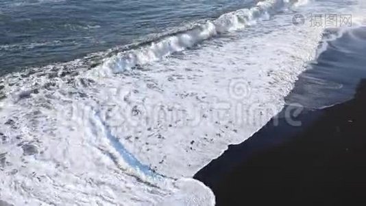 波浪跑到海滩上。 白色泡沫从黑色海滩的背景上的波浪。 海洋冲浪视频