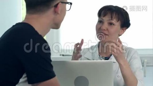 友好的女医生咨询坐在办公桌旁的男性病人咨询笔记本电脑视频