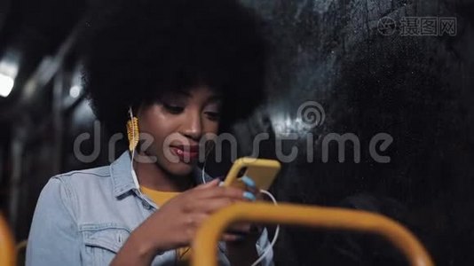 漂亮的非裔美国年轻女性在公共交通工具上使用智能手机。 晚上。 城市灯光背景。视频