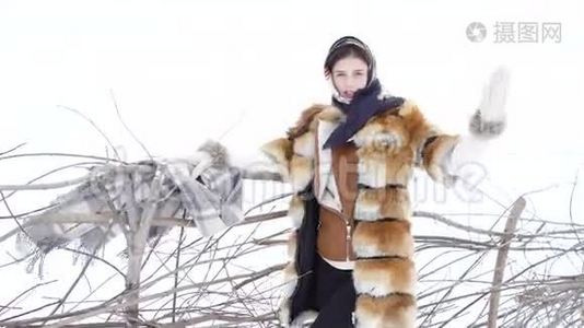 冬天，穿暖和衣服的女孩举起手，在木栅栏附近摆姿势视频
