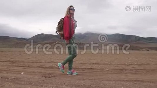 带背包的游客在山上的肖像。 女孩旅行者在恶劣的天气里行走在山区视频