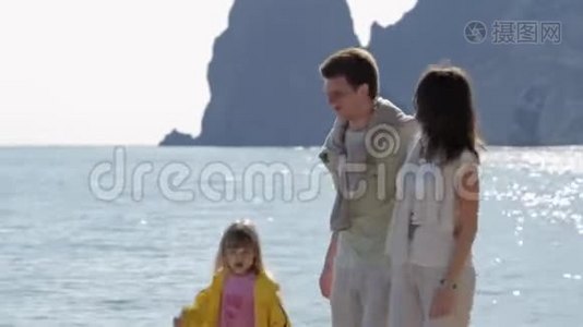 快乐的父母和女儿在阳光明媚的日子里走在海岸上视频