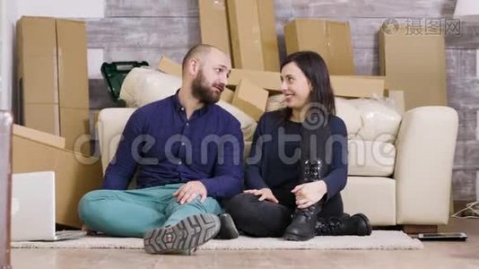 漂亮的年轻夫妇坐在他们新公寓的地板上视频