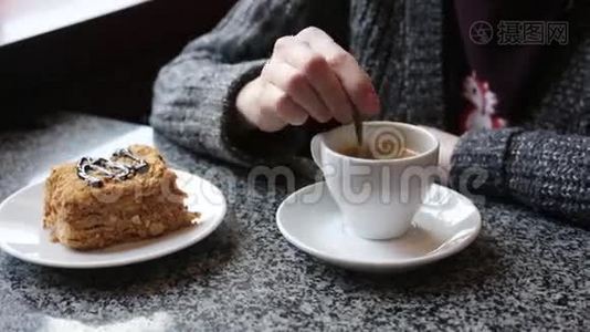 那个女孩在一杯白咖啡里搅拌糖。 女性手拿着一杯美式浓缩咖啡。视频