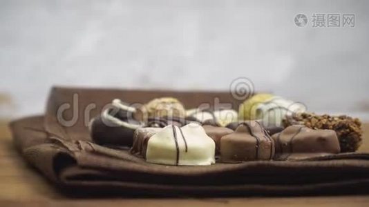 手工制作的巧克力糖果落在木制背景上，慢动作的美味糖果视频