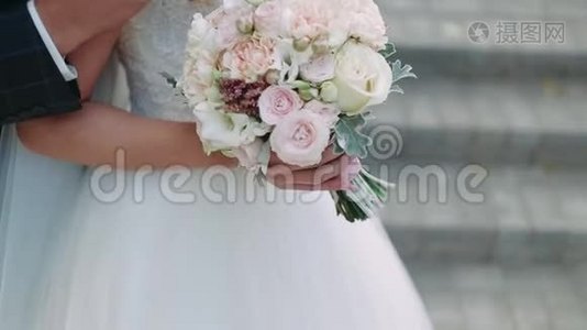 快乐的新娘和新郎。 你的手。 新郎用花束拥抱新娘。 幸福的眼泪。 特写视频