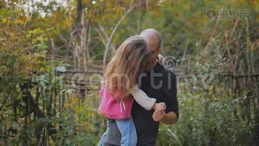爸爸抱在怀里。 爸爸和女儿在秋天的公园里玩旋转和跳舞的乐趣。 慢动作视频