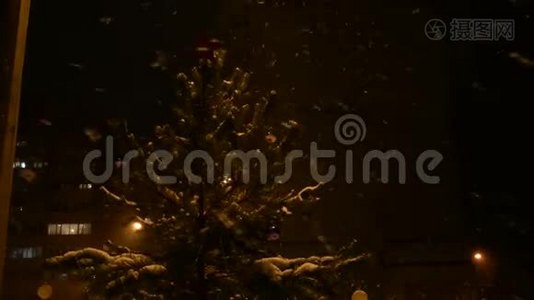 夜晚，一棵装饰好的圣诞树矗立在街道上，降下一场雪，头顶上是一颗红星视频