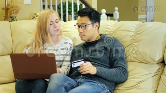 多种族夫妇在网上购物。 持有信用卡的亚裔男子，带手提电脑的高加索女子视频