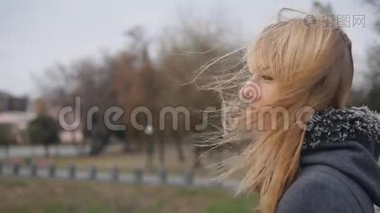 年轻的女孩站在街上，她的头发在风中飘扬。 慢镜头视频