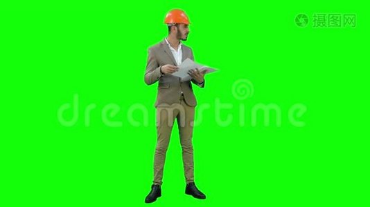 年轻的建筑师戴着头盔，在绿色屏幕上查看施工图，Chroma键。视频