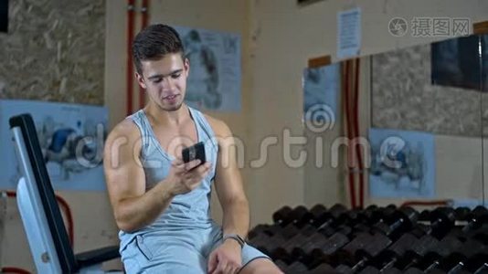 运动员锻炼后坐在健身中心，在网上聊天智能手机视频