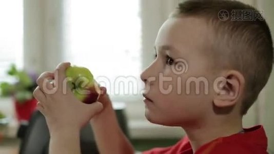 一个脸严肃的小男孩咬了一个苹果。视频