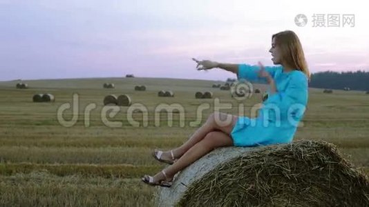 美丽的年轻女子坐在干草堆上跳舞。视频