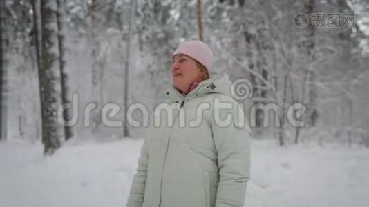 成年女性，金发，藏在粉红色的帽子下面，穿着白色的冬装，站在中间视频