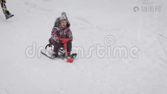 幸福的小女孩坐在她的红色雪橇上，从山上滑下来。 小公主花了她的钱视频