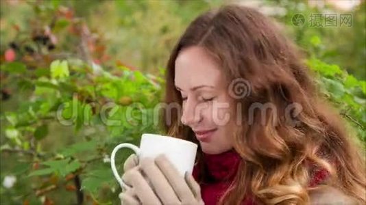 可爱的女孩在秋天喝一杯热饮料视频